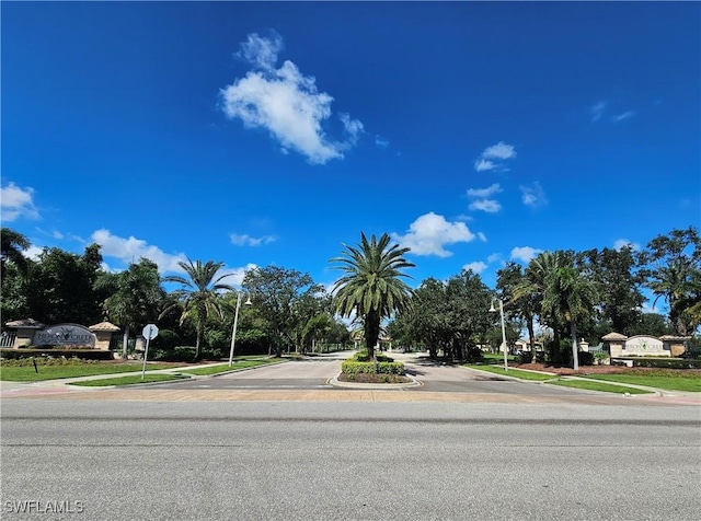 view of street with sidewalks, traffic signs, street lights, and curbs