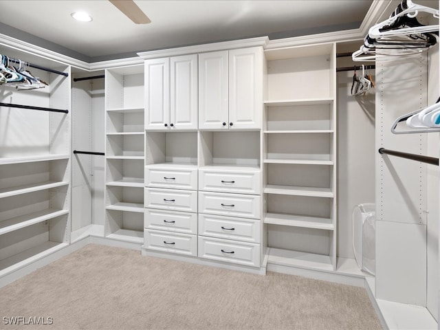 walk in closet with light carpet and ceiling fan