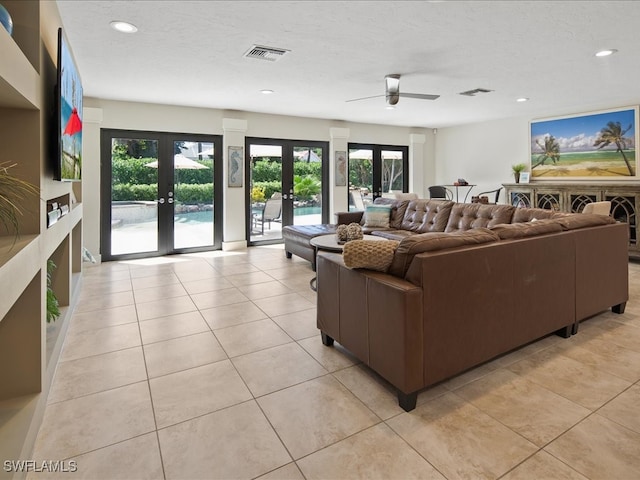 tiled living room featuring ceiling fan, a textured ceiling, and french doors