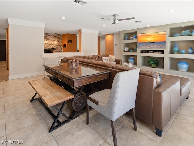 tiled dining room featuring a brick fireplace, built in features, and ceiling fan