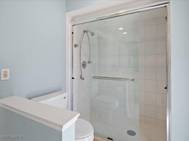 bathroom featuring a shower with shower door and toilet