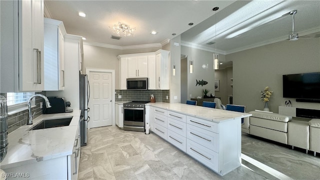 kitchen with appliances with stainless steel finishes, white cabinets, kitchen peninsula, ornamental molding, and sink