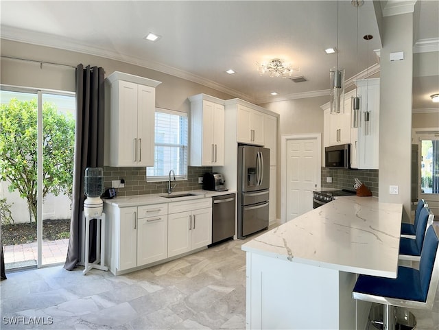 kitchen featuring white cabinets, appliances with stainless steel finishes, sink, and a wealth of natural light