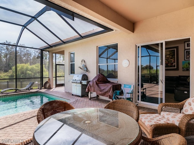 view of swimming pool with glass enclosure, area for grilling, and a patio area