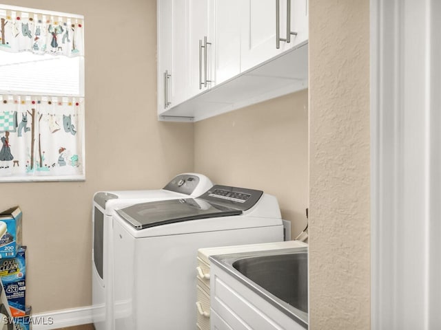 washroom featuring separate washer and dryer, cabinets, and sink