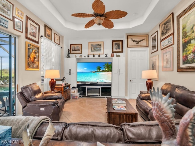 living room with a tray ceiling and ceiling fan