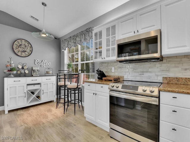 kitchen with lofted ceiling, white cabinets, and stainless steel appliances