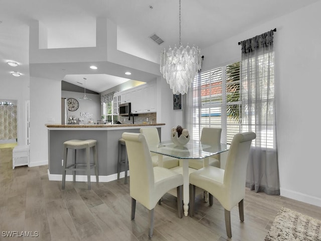 dining room with lofted ceiling, a chandelier, and light hardwood / wood-style floors