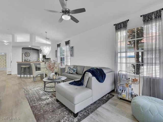 living room featuring a healthy amount of sunlight, light hardwood / wood-style flooring, and ceiling fan with notable chandelier