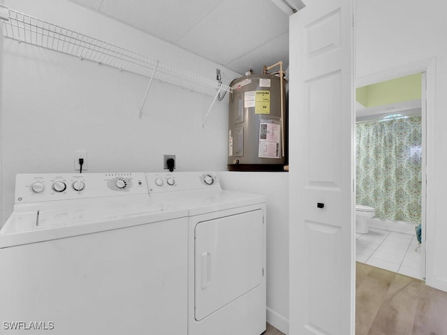 clothes washing area featuring water heater, independent washer and dryer, and light wood-type flooring