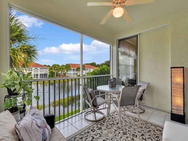 sunroom featuring a water view and ceiling fan