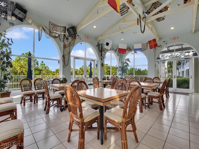 dining area with beam ceiling, light tile patterned flooring, and high vaulted ceiling