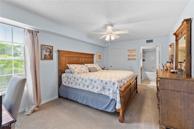 carpeted bedroom featuring a textured ceiling, ensuite bath, and ceiling fan