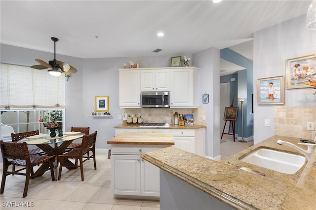 9235 Tesoro Ln Unit 4-102, Naples, FL 34114 - kitchen with a sink, a ceiling fan, gas stovetop, stainless steel microwave, and backsplash