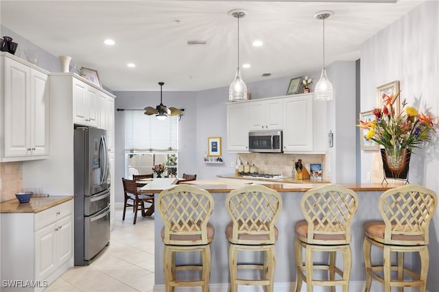 kitchen featuring stainless steel appliances, white cabinetry, kitchen peninsula, and hanging light fixtures