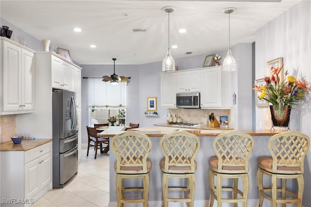 9235 Tesoro Ln Unit 4-102, Naples, FL 34114 - kitchen featuring tasteful backsplash, appliances with stainless steel finishes, a kitchen bar, and white cabinetry