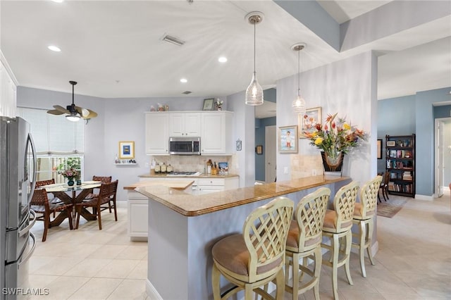 9235 Tesoro Ln Unit 4-102, Naples, FL 34114 - kitchen with light tile patterned floors, backsplash, white cabinets, and stainless steel appliances