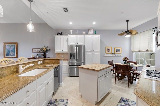 kitchen with stainless steel appliances, white cabinetry, light stone counters, and sink