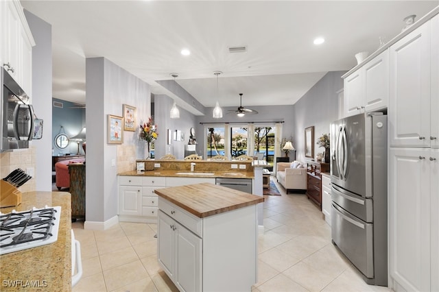 kitchen with white cabinets, stainless steel appliances, hanging light fixtures, and a kitchen island