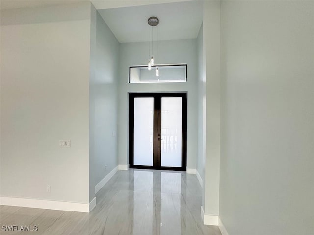 entryway with light wood-type flooring, a towering ceiling, and french doors