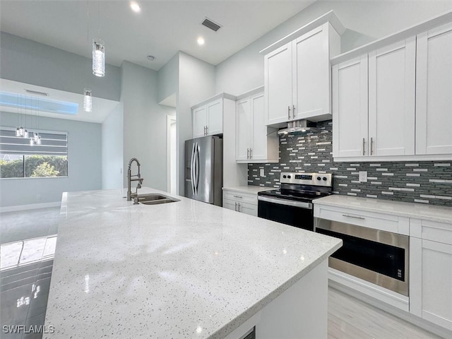 kitchen featuring pendant lighting, sink, white cabinetry, stainless steel appliances, and light stone countertops