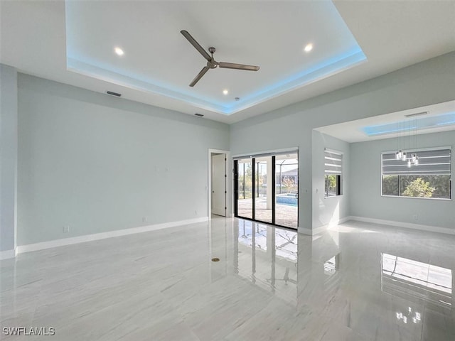 spare room with ceiling fan with notable chandelier, a raised ceiling, and french doors