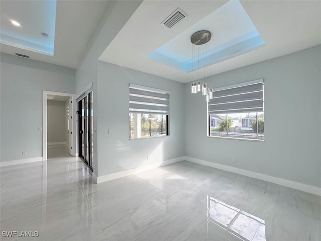 spare room featuring a raised ceiling and a chandelier