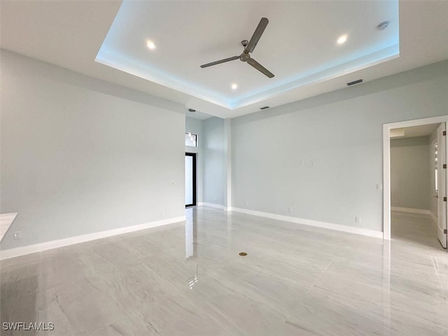 spare room featuring ceiling fan and a raised ceiling