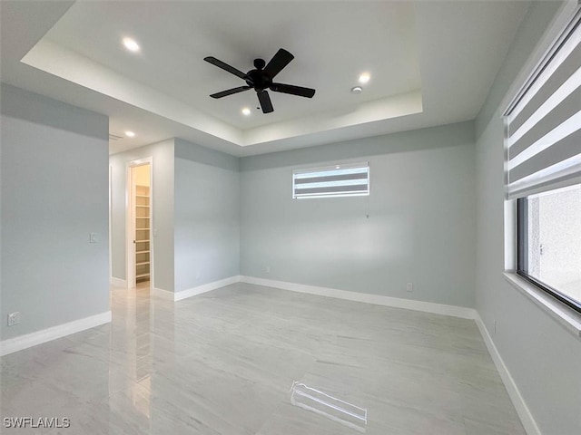 spare room with a raised ceiling and ceiling fan