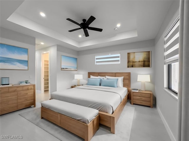 bedroom with a tray ceiling, a spacious closet, and ceiling fan