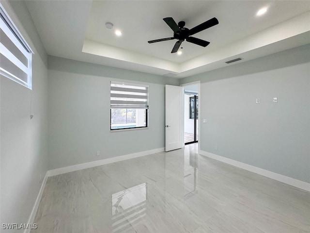 unfurnished room featuring a raised ceiling and ceiling fan