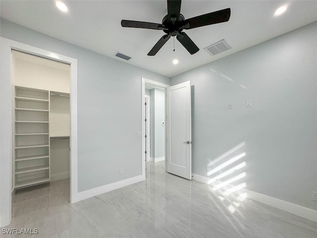 unfurnished bedroom featuring a closet, ceiling fan, and a walk in closet