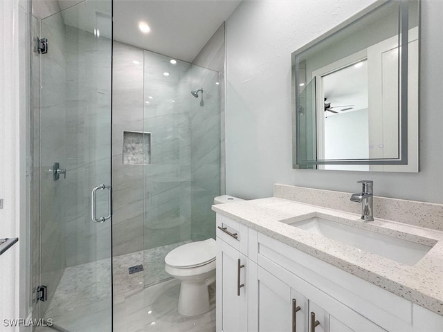 bathroom with ceiling fan, vanity, toilet, and an enclosed shower