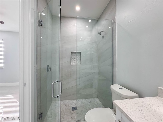 bathroom with a shower with shower door, vanity, and toilet