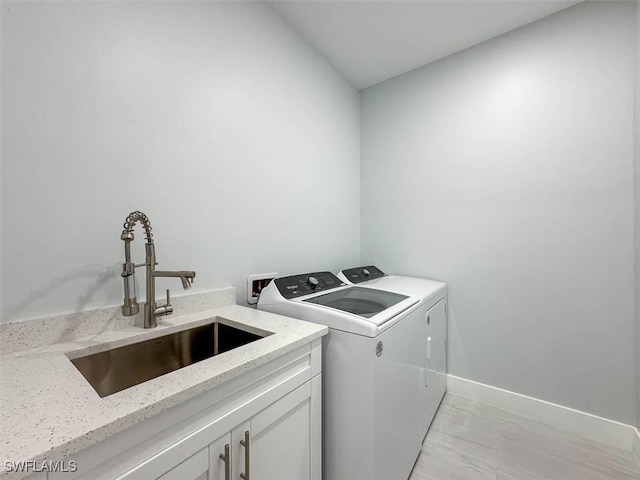 laundry area with washer and clothes dryer, light hardwood / wood-style floors, sink, and cabinets