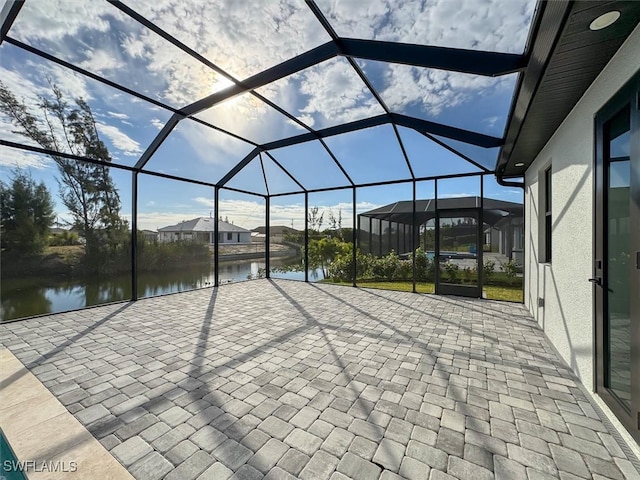 view of patio with a lanai and a water view