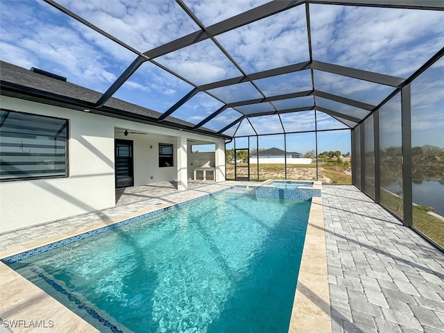 view of swimming pool with glass enclosure, an in ground hot tub, a water view, ceiling fan, and a patio area