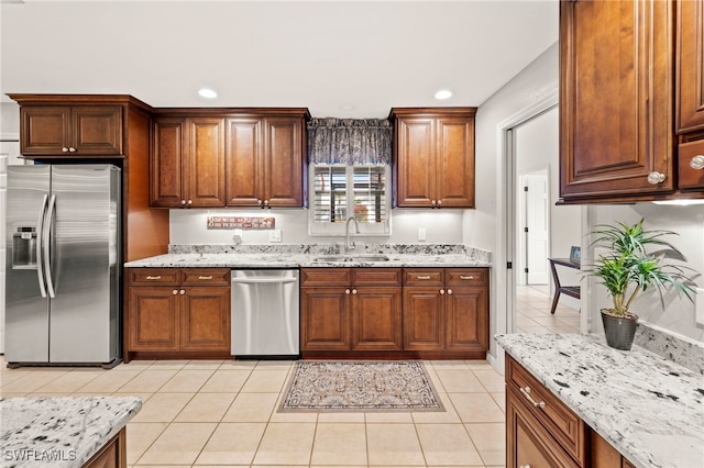 kitchen with light tile patterned floors, appliances with stainless steel finishes, sink, and light stone countertops