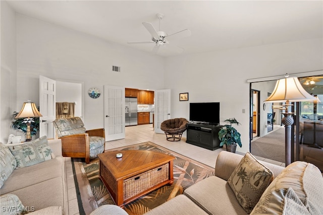 tiled living room featuring ceiling fan and a towering ceiling