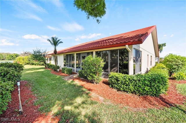 back of property featuring a yard and a sunroom