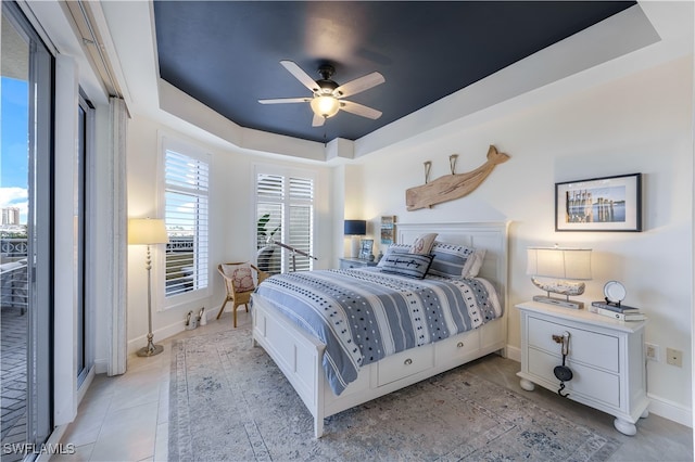 tiled bedroom with ceiling fan and a tray ceiling