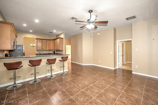 kitchen featuring ceiling fan, sink, kitchen peninsula, stainless steel appliances, and a breakfast bar area