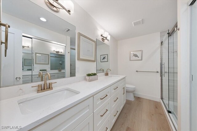 bathroom with a shower with door, vanity, wood-type flooring, and toilet