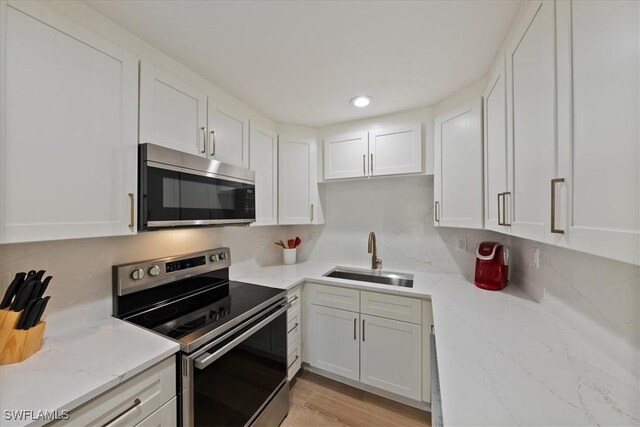 kitchen featuring sink, white cabinetry, stainless steel appliances, and light wood-type flooring