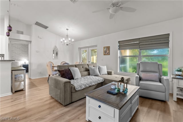 living room featuring ceiling fan with notable chandelier, lofted ceiling, and light hardwood / wood-style flooring