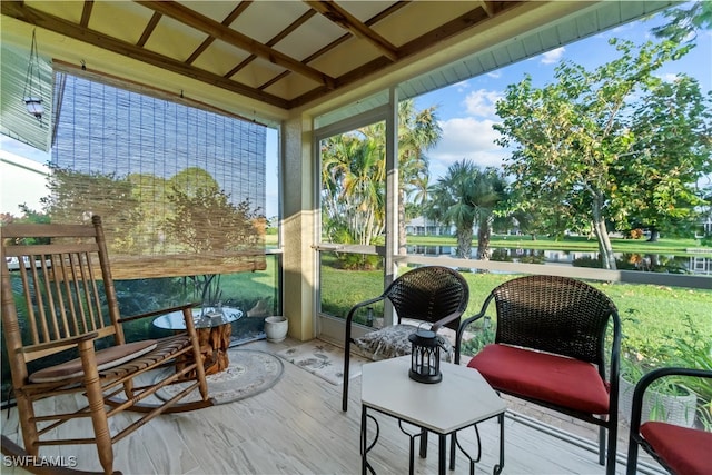 sunroom / solarium featuring a water view and lofted ceiling