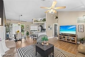 living room with ceiling fan with notable chandelier, wood-type flooring, and lofted ceiling