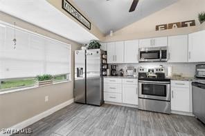 kitchen featuring lofted ceiling, stainless steel appliances, white cabinets, and light wood-type flooring