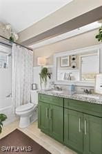 bathroom with curtained shower, vanity, and toilet