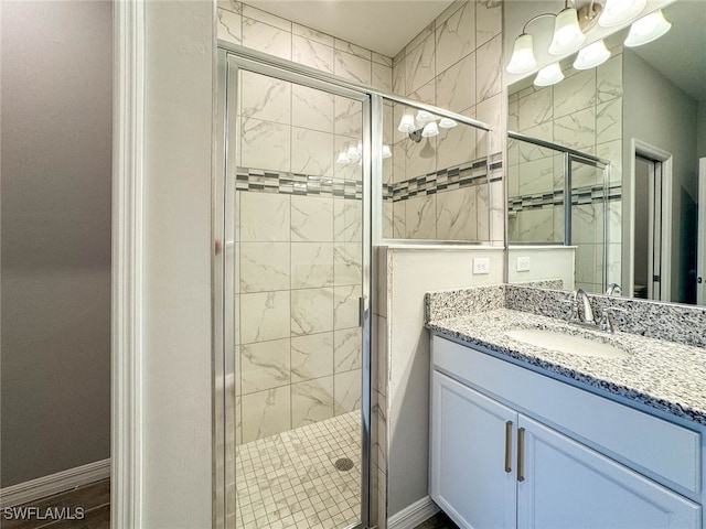 bathroom featuring a shower with door and vanity